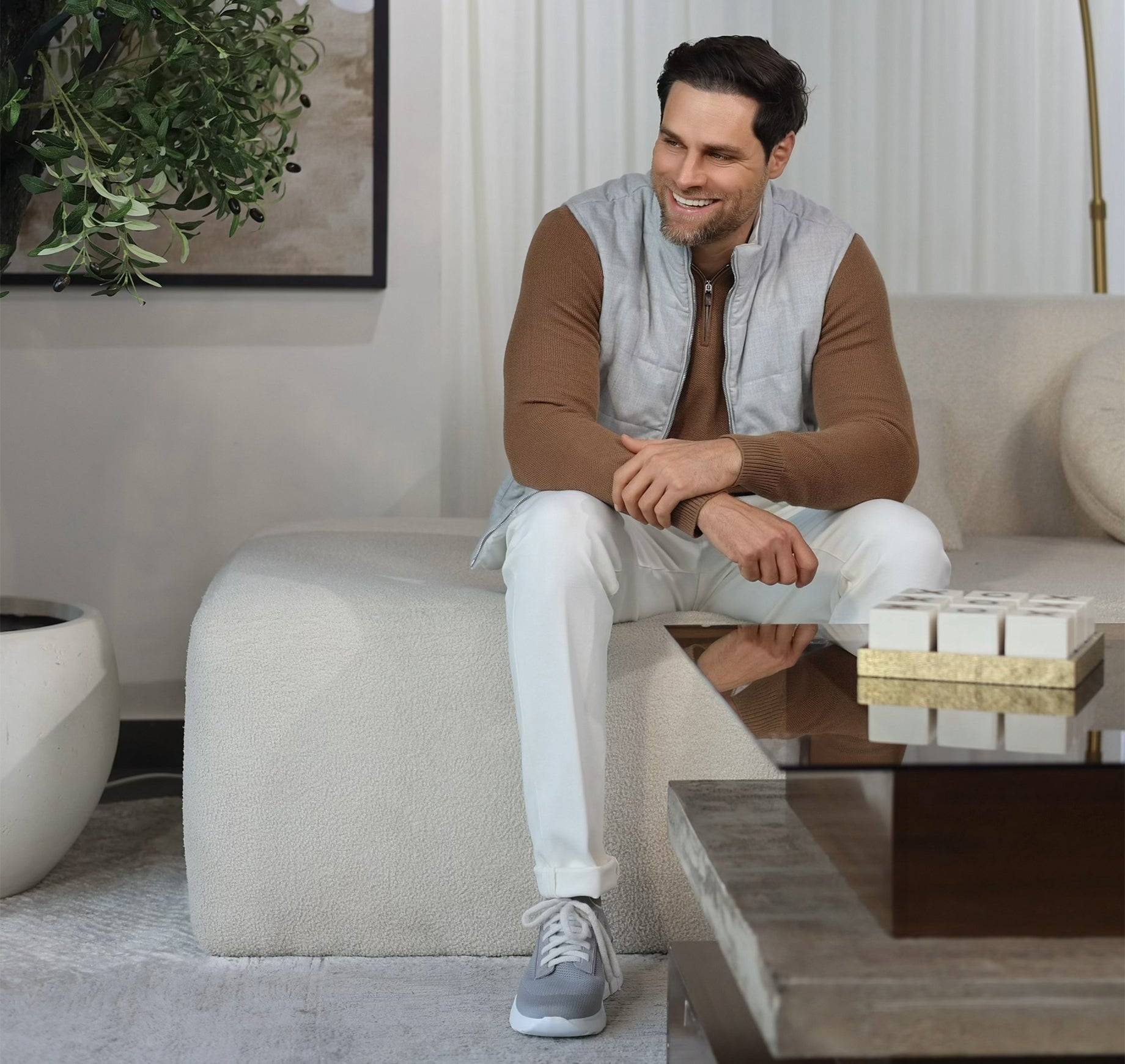 Man sitting on a beige ottoman in a modern living room.